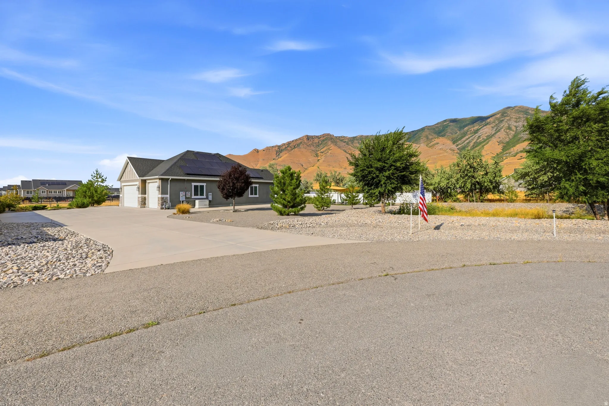 Ranch-style residence featuring a multi-car driveway, attached garage, and solar panels