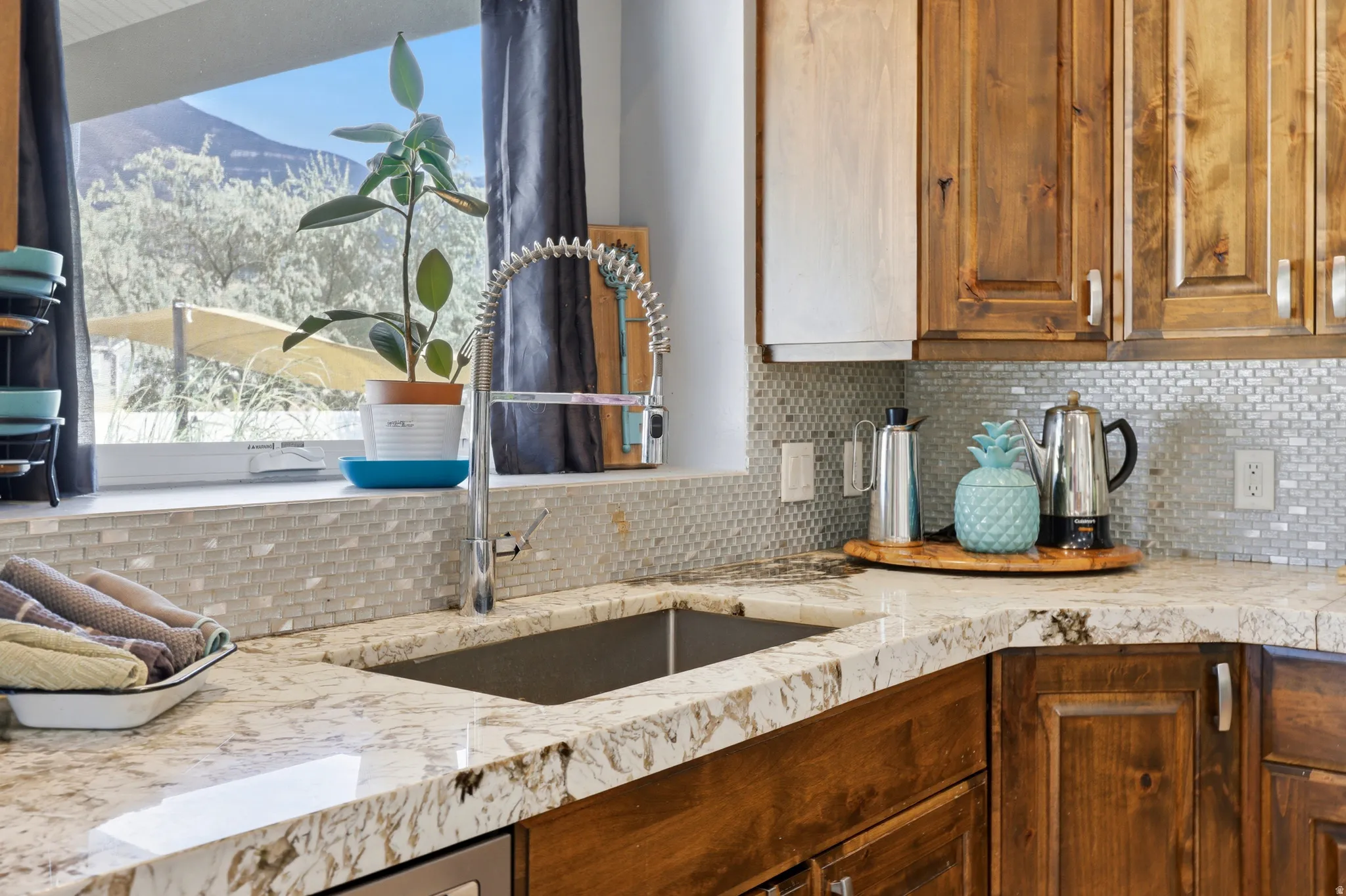 Kitchen featuring granite-style countertops, mosaic tile backsplash, and a stainless steel undermount sink with a pull-down faucet