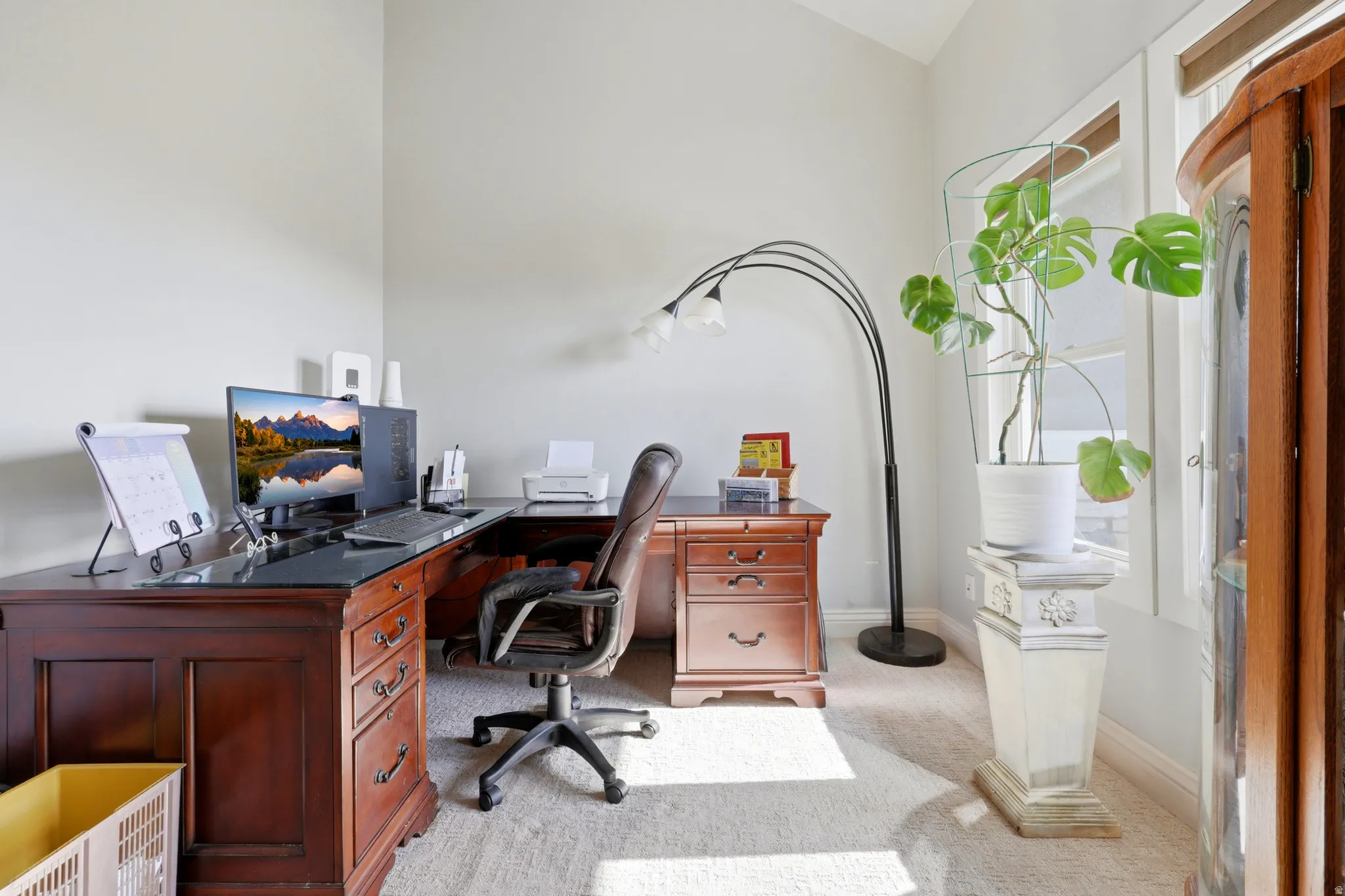 Dedicated workspace featuring a large L-shaped desk with dark wood finish and integrated storage