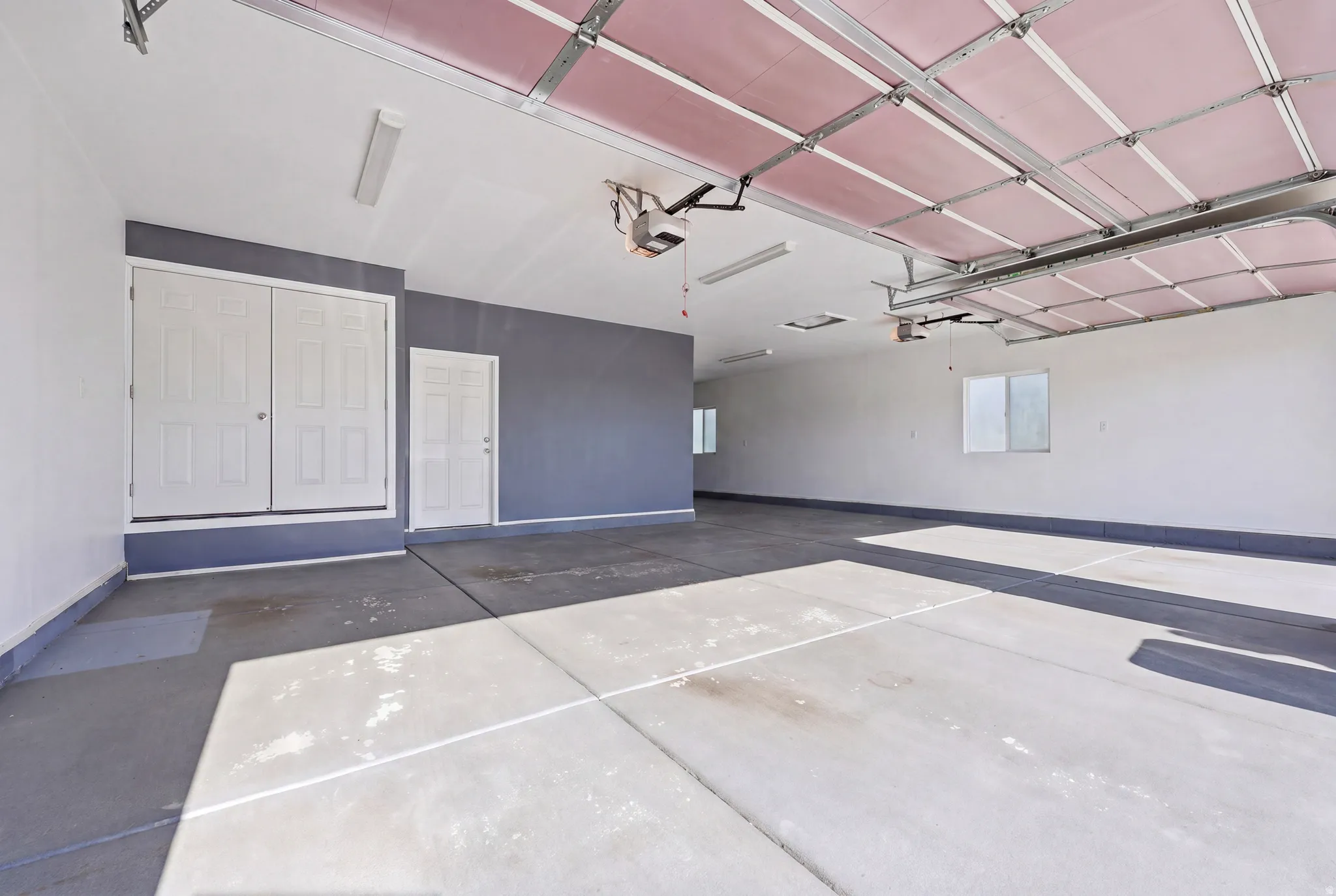 Spacious garage featuring concrete flooring, white walls, and a grey accent wall