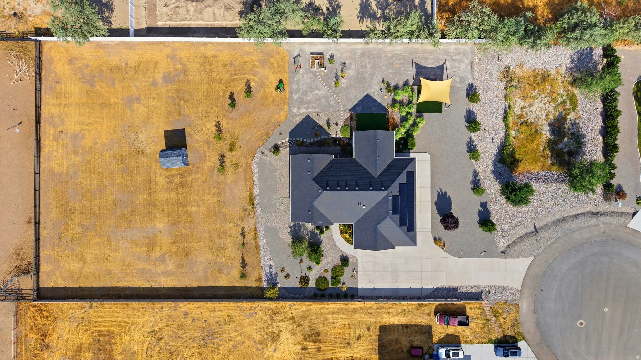 Asymmetrical roofline on a large single-story residence with a concrete driveway and an expansive gravel yard