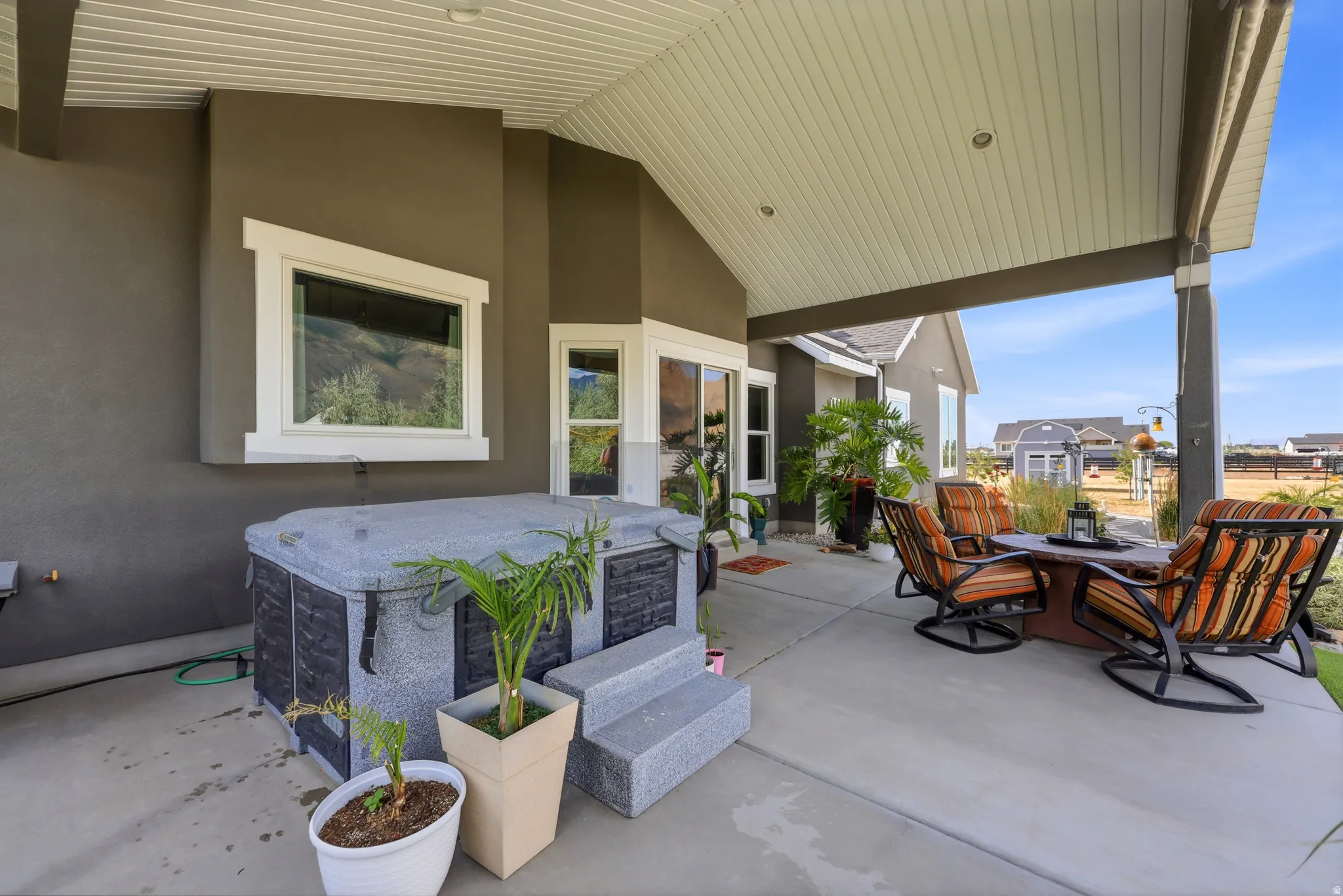 Covered patio with a concrete surface, featuring a built-in hot tub, recessed lighting, and a stucco exterior