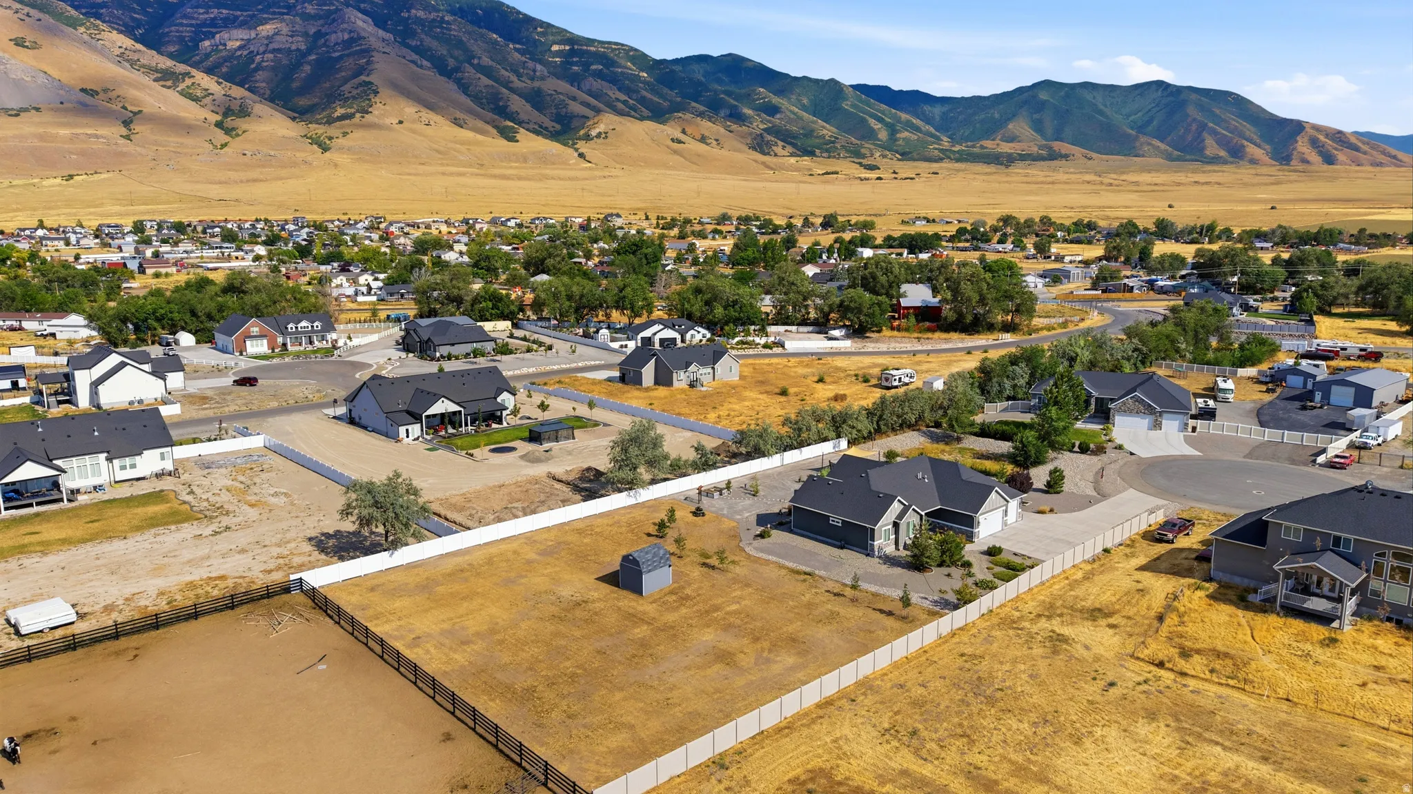 Expansive property featuring a modern ranch-style residence with a two-car garage, surrounded by a white privacy fence