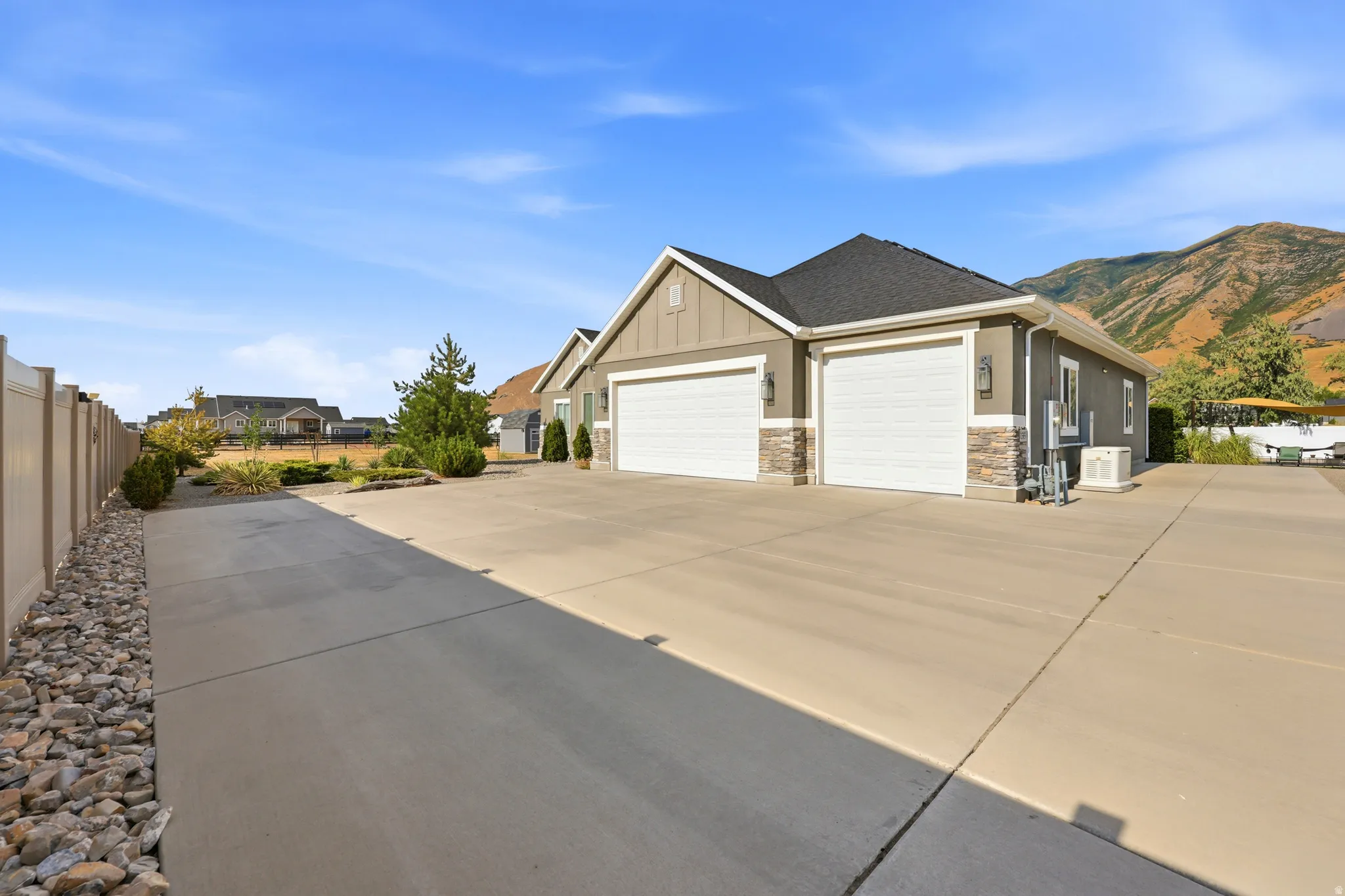 Two-car garage with white doors, stone accents, and exterior lighting fixtures