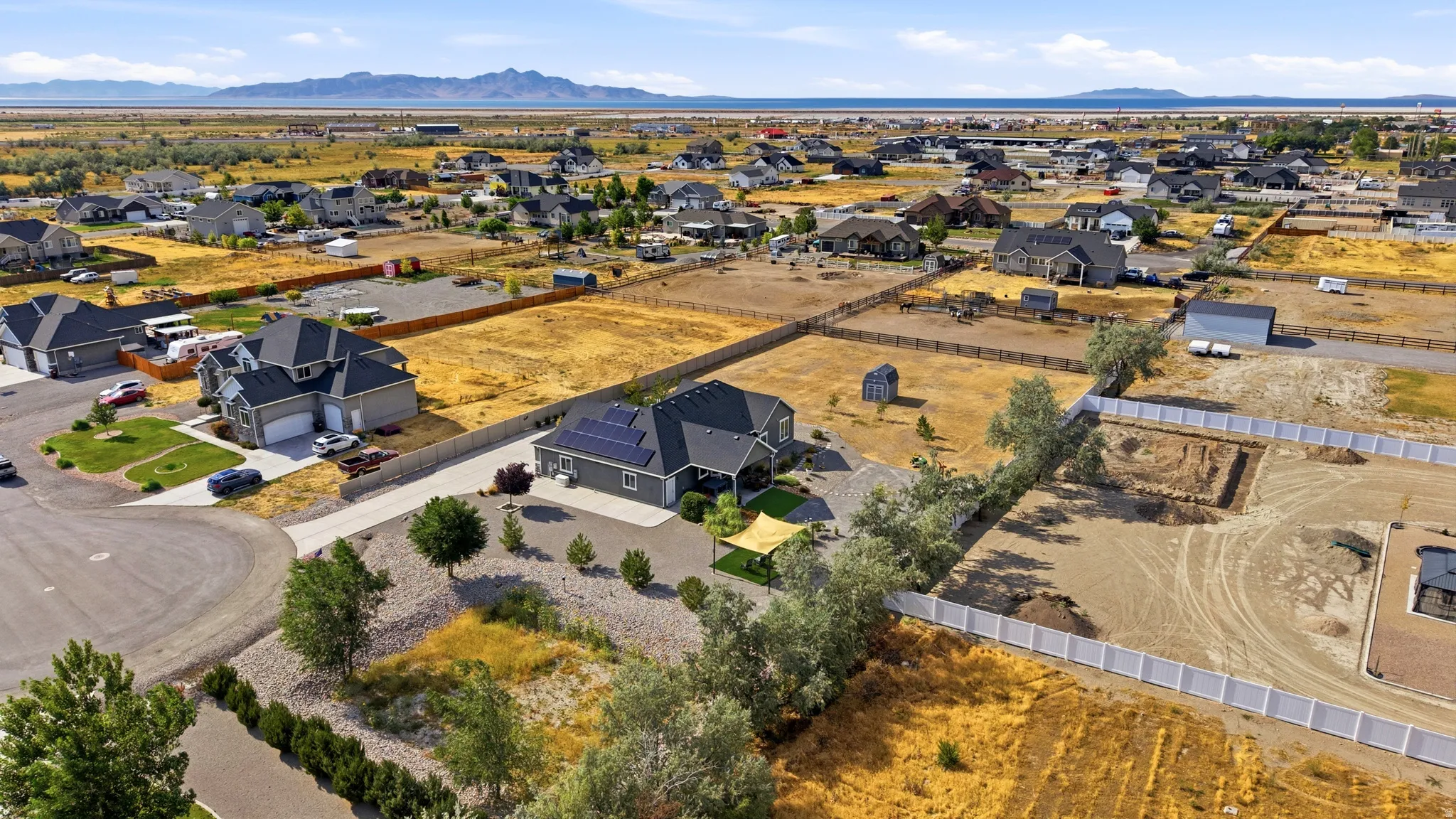Expansive lot featuring a contemporary single-story residence with dark roofing, solar panel installation, and a paved driveway
