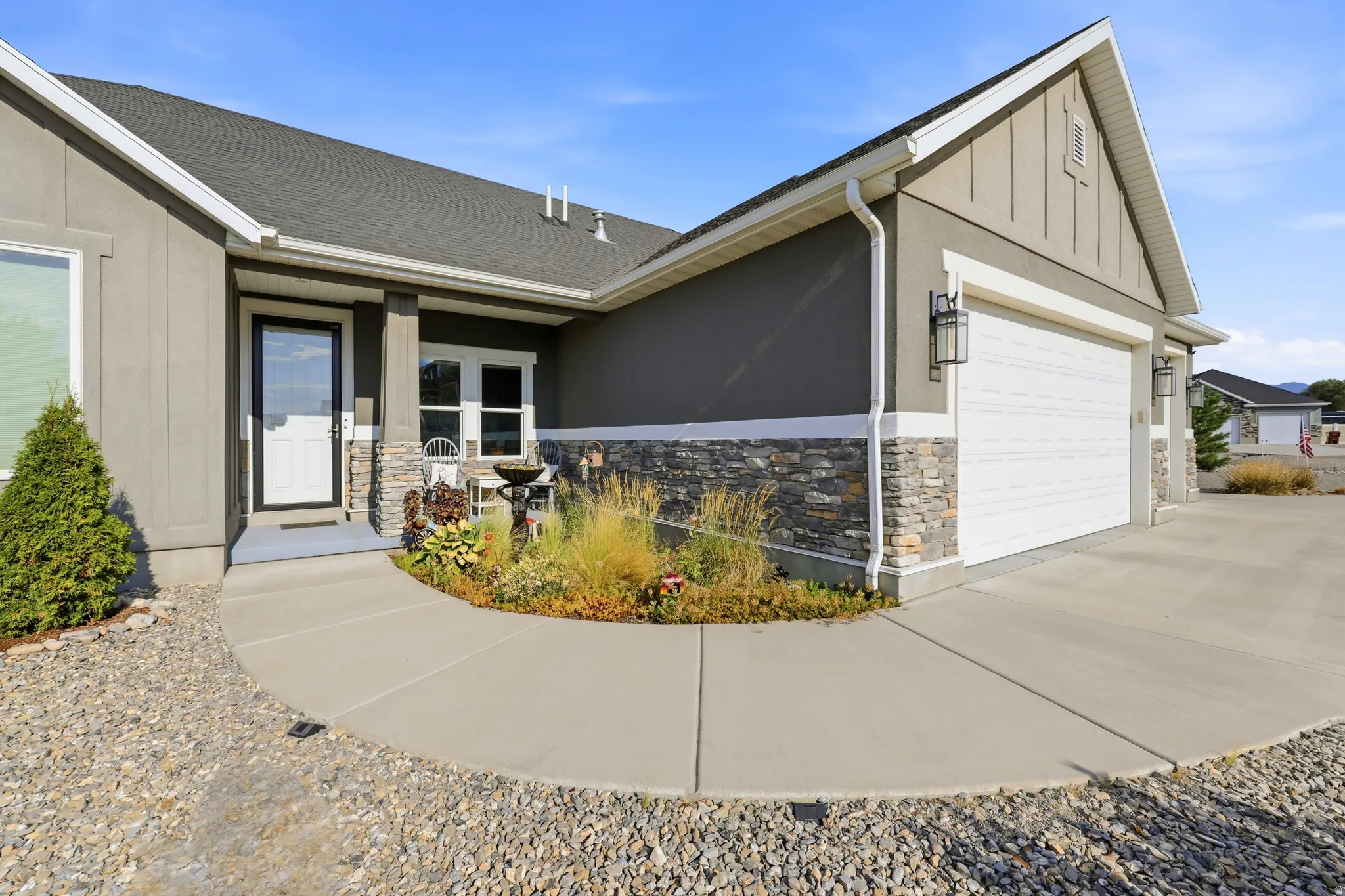 Contemporary home exterior featuring stone veneer accents, an attached two-car garage, and a concrete driveway