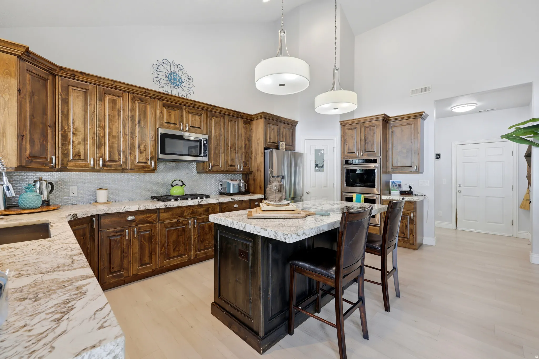 Kitchen featuring wood-finish cabinetry, light-toned countertops, and a central island with bar seating