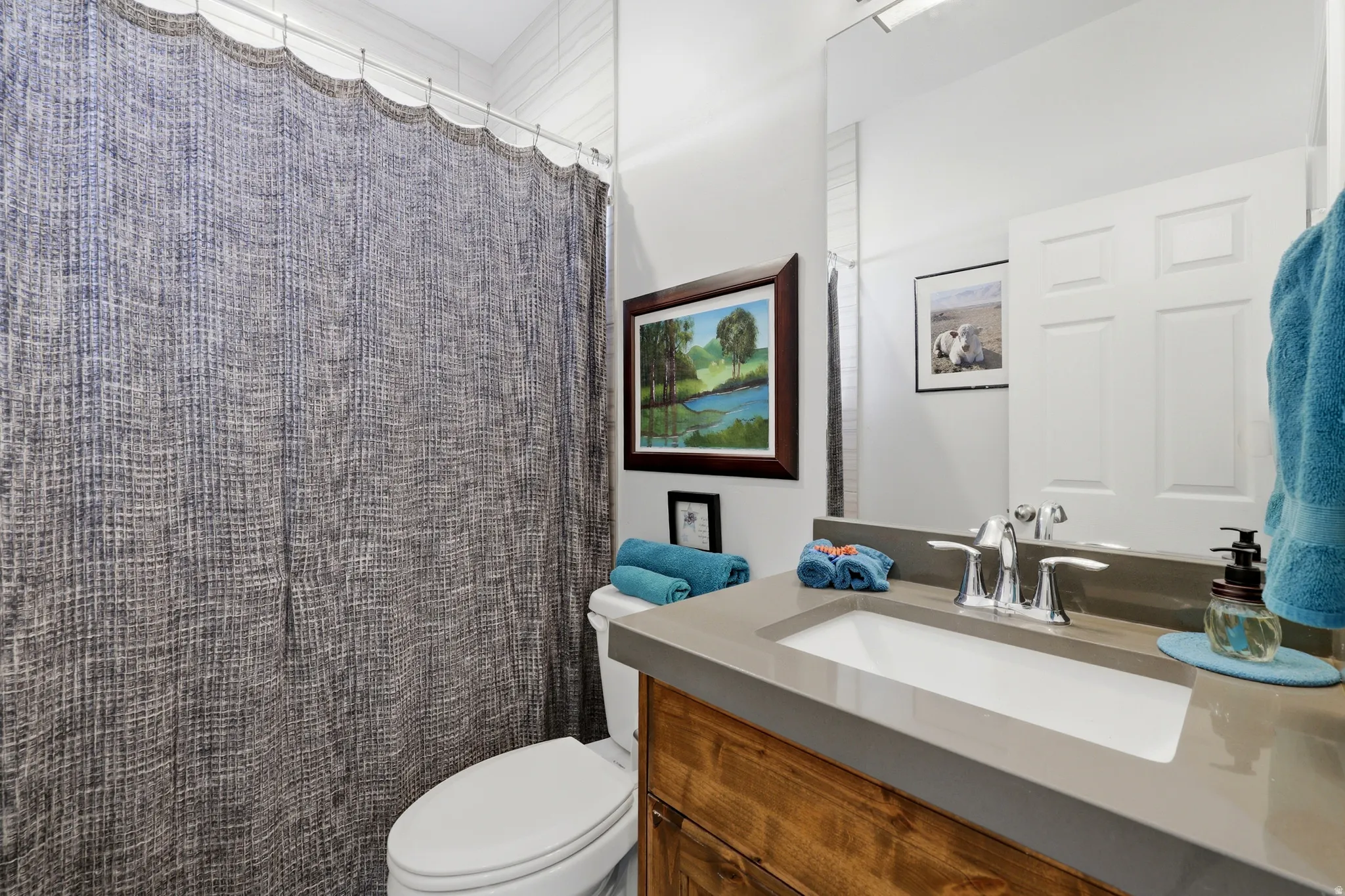 Bathroom featuring a single vanity with a rectangular sink, a light-toned countertop, and a wood-finish cabinet
