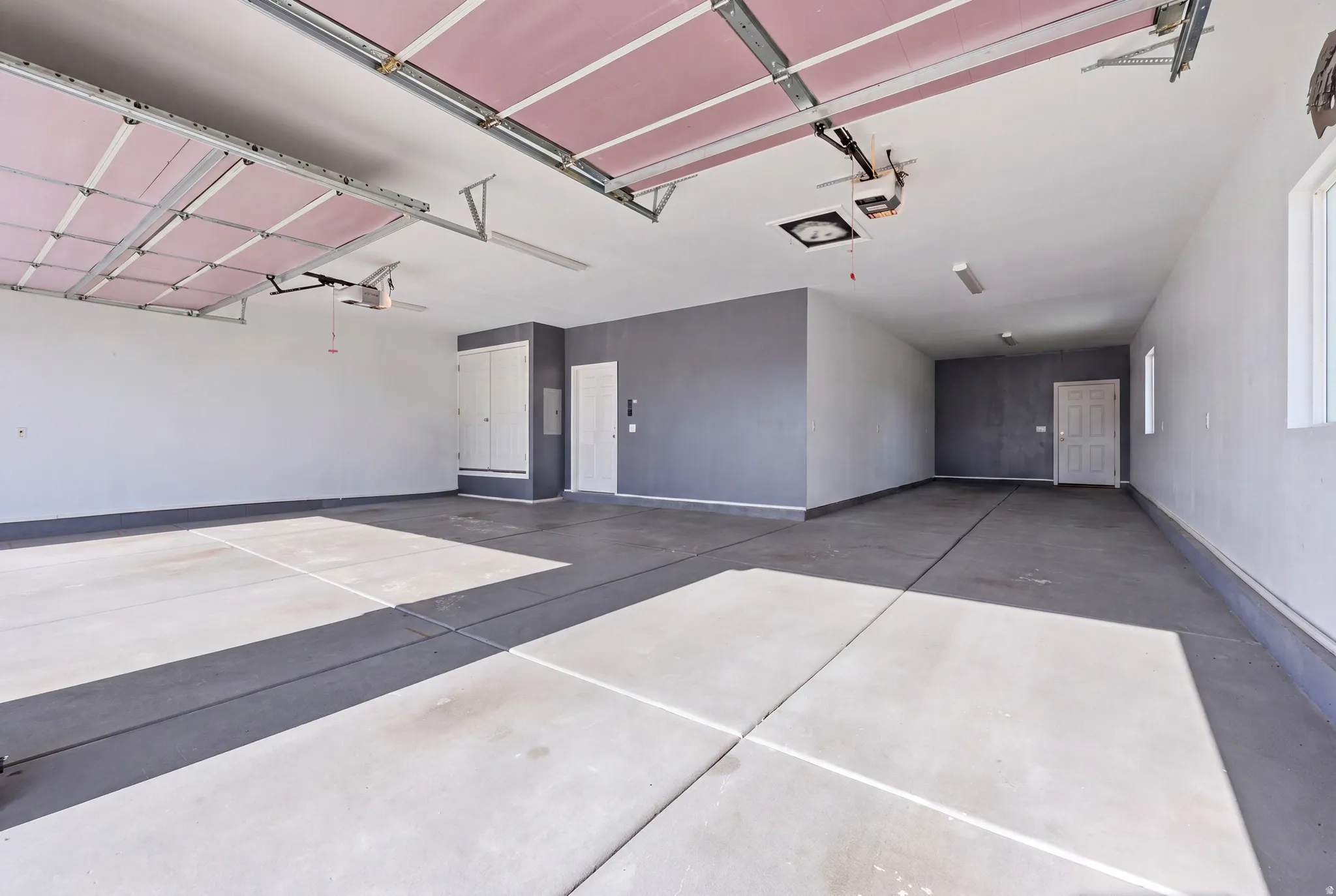 Spacious garage featuring two overhead doors, concrete flooring, and built-in storage cabinetry