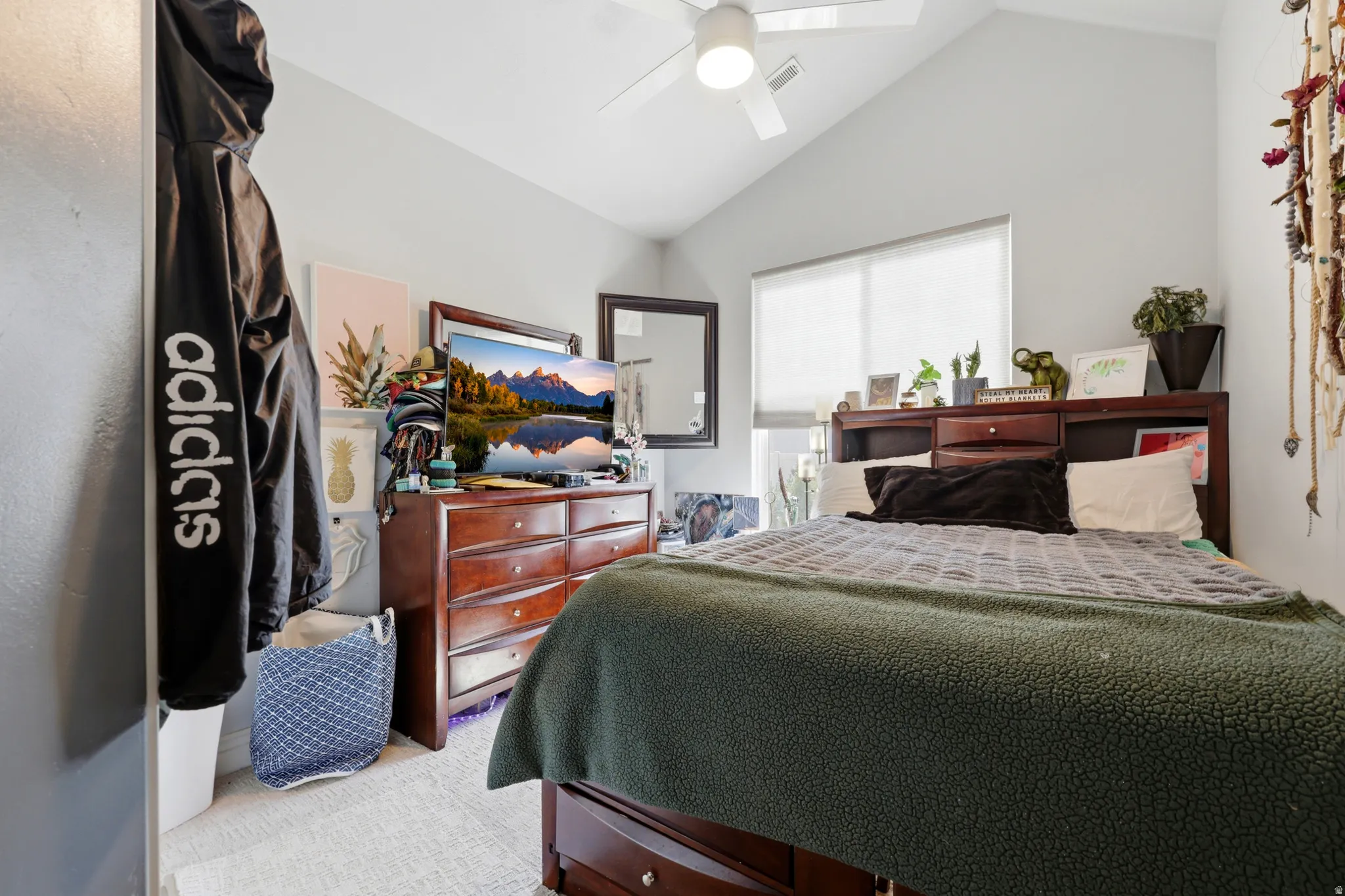 Vaulted ceiling bedroom with a ceiling fan, recessed window with a pull-down shade, and light-toned carpet flooring