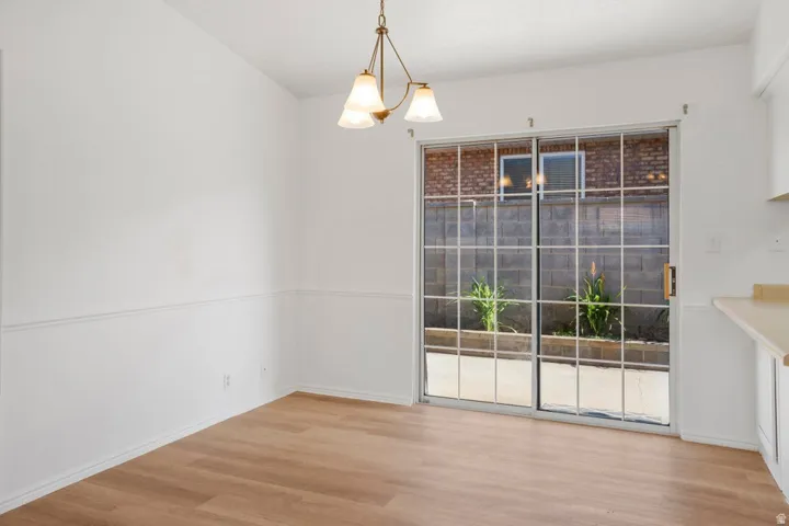 Dining area featuring wood-finish flooring, white paneled walls, and a multi-light chandelier