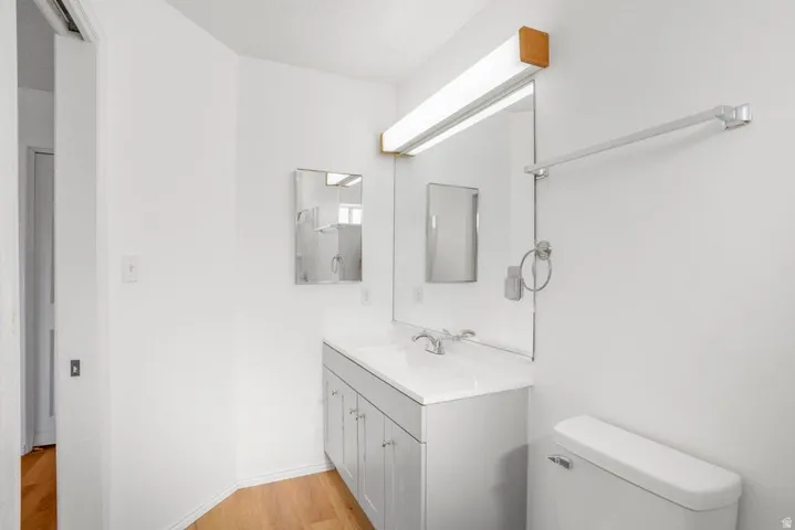 Bathroom featuring a vanity with an integrated sink, a large mirror, and a wall-mounted light fixture