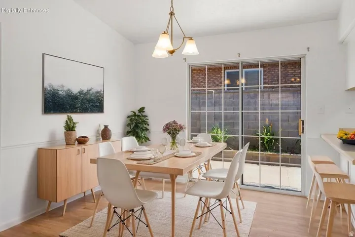 Dining area featuring wood-finish flooring, white wall paneling, and a contemporary chandelier