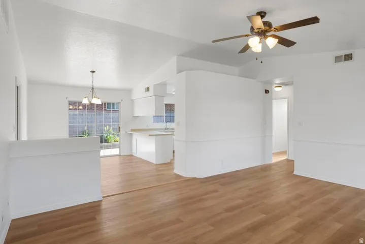 Open-concept living area featuring wood-finish flooring, vaulted ceilings, and a ceiling fan with integrated lighting