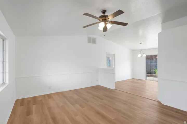 Living area with wood-finish flooring, white walls with wainscoting, and a ceiling fan with light fixture