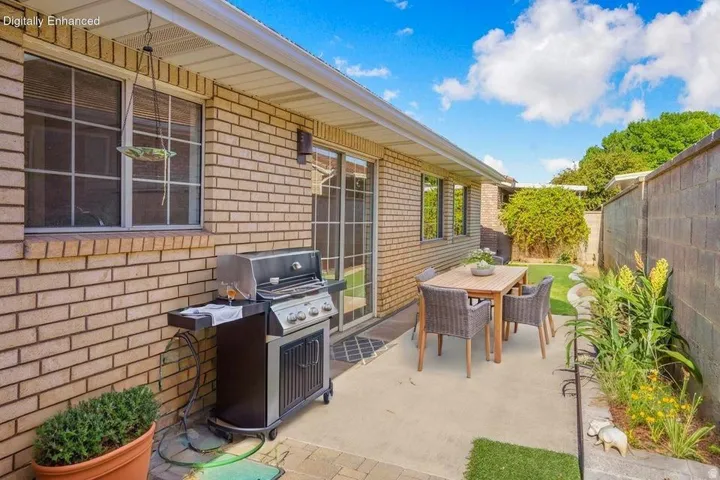 Private outdoor patio space featuring a concrete slab, adjacent garden bed, and block wall perimeter