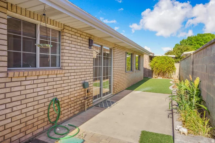 Private outdoor area featuring a concrete patio, artificial turf, and block wall fencing
