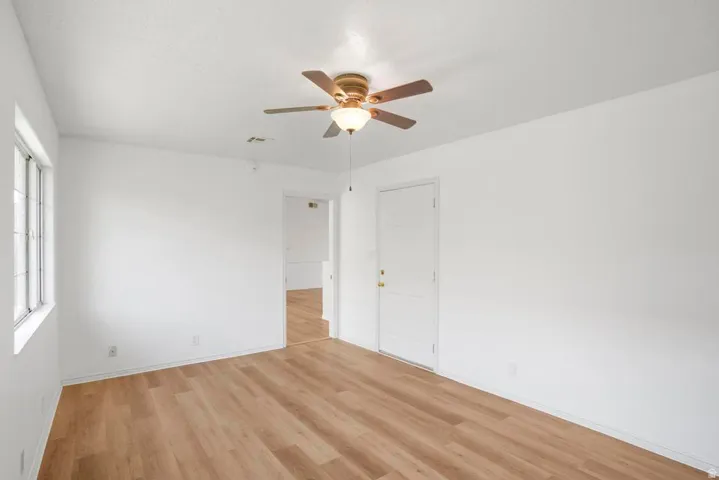 Bright interior featuring wood-finish flooring, white walls, and a ceiling fan with light fixture