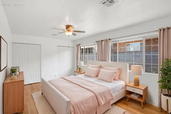 Bedroom featuring wood-finish flooring, a ceiling fan with integrated lighting, and multiple windows with horizontal grids