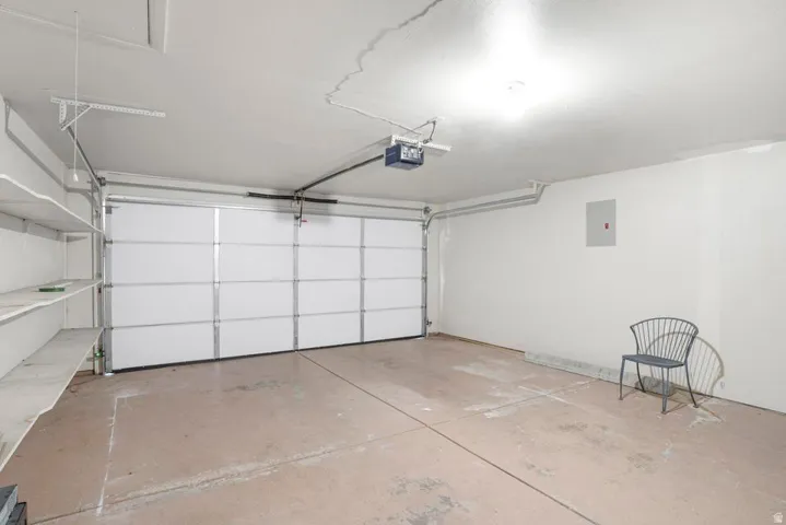 Garage with a sectional overhead door, concrete flooring, and built-in shelving