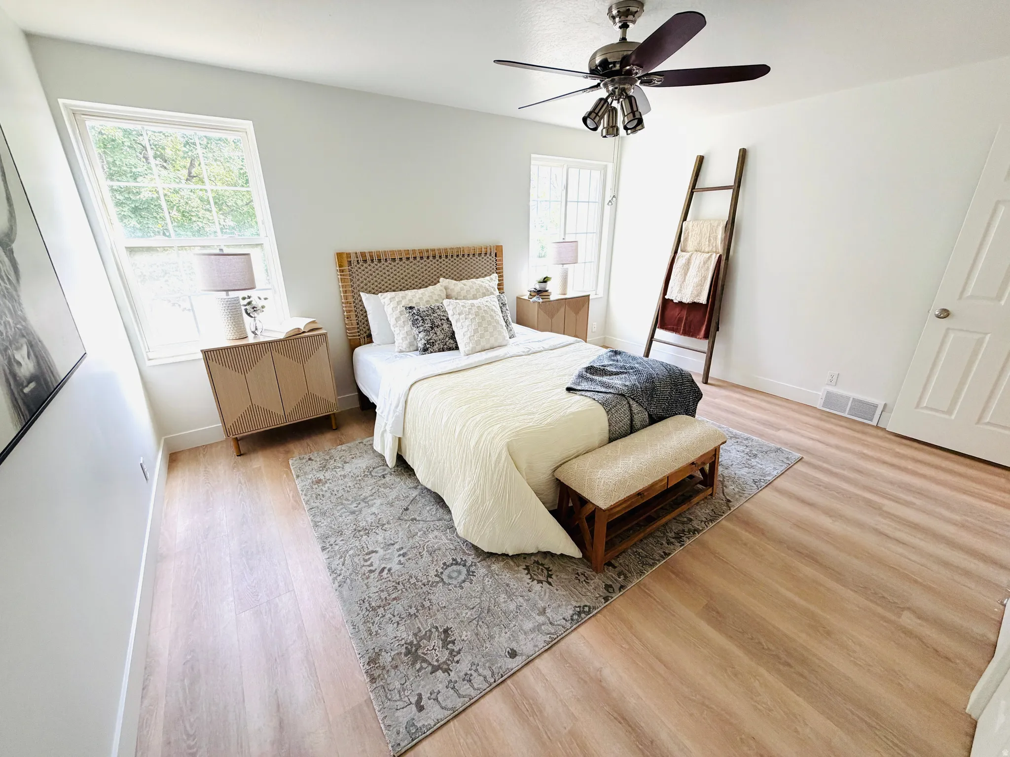 Bright room featuring light wood-finish flooring, white baseboards, and a ceiling fan with integrated lighting