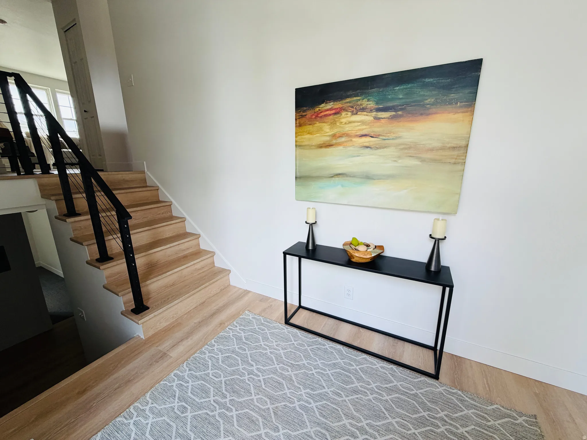 Staircase featuring wood-finish treads and risers, complemented by a contemporary black metal handrail with cable infill