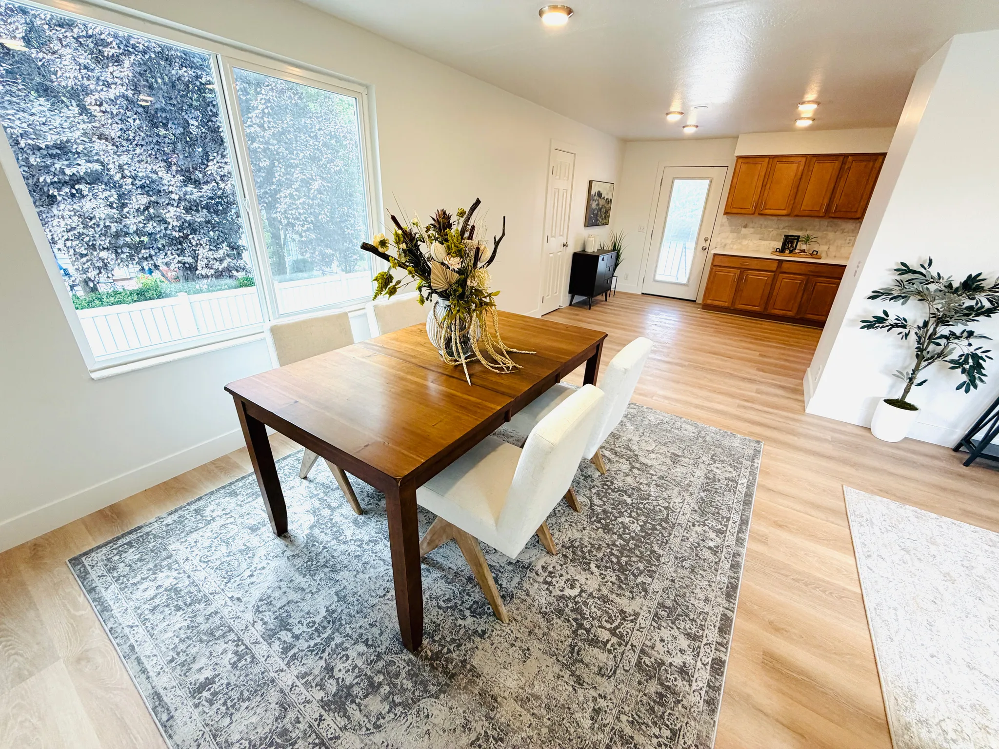 Open-concept dining area featuring wood-finish flooring, ample natural light from large windows, recessed lighting, and a neutral color palette