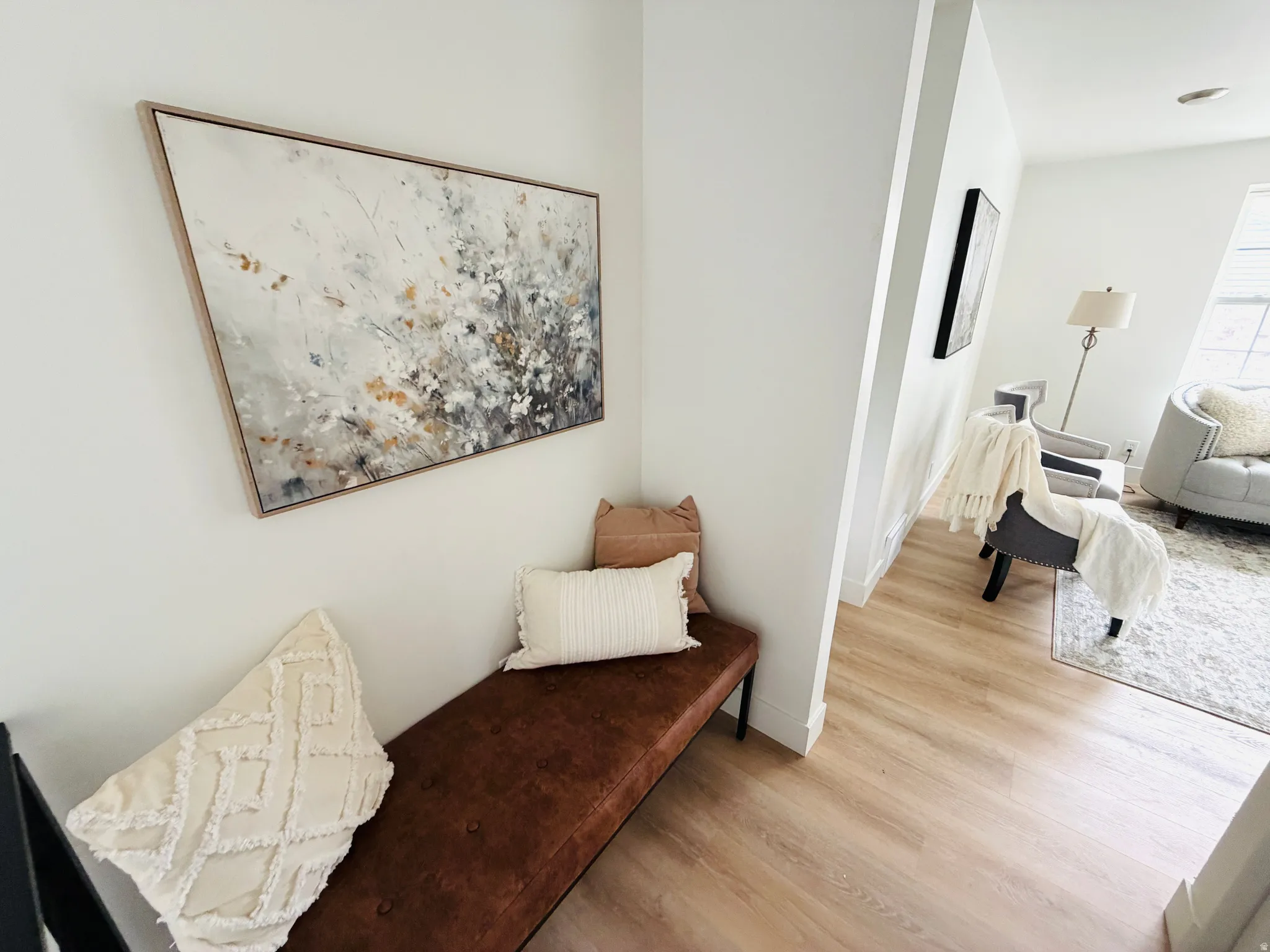 Light-toned wood-finish flooring extends through the entryway, complemented by white baseboards and walls