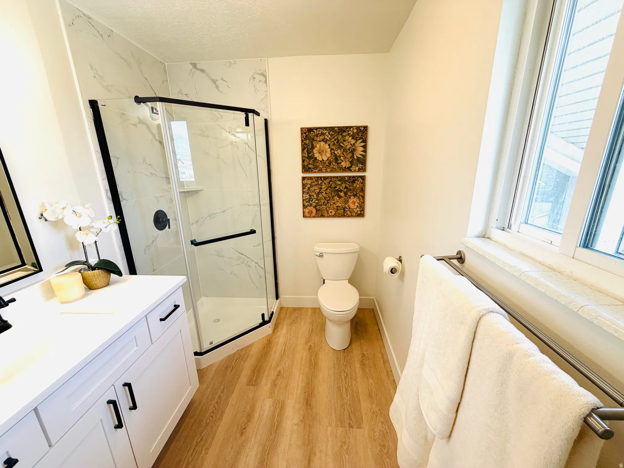 Bathroom featuring a corner glass-enclosed shower with black framing, white marble-style subway tile, and a built-in shower niche