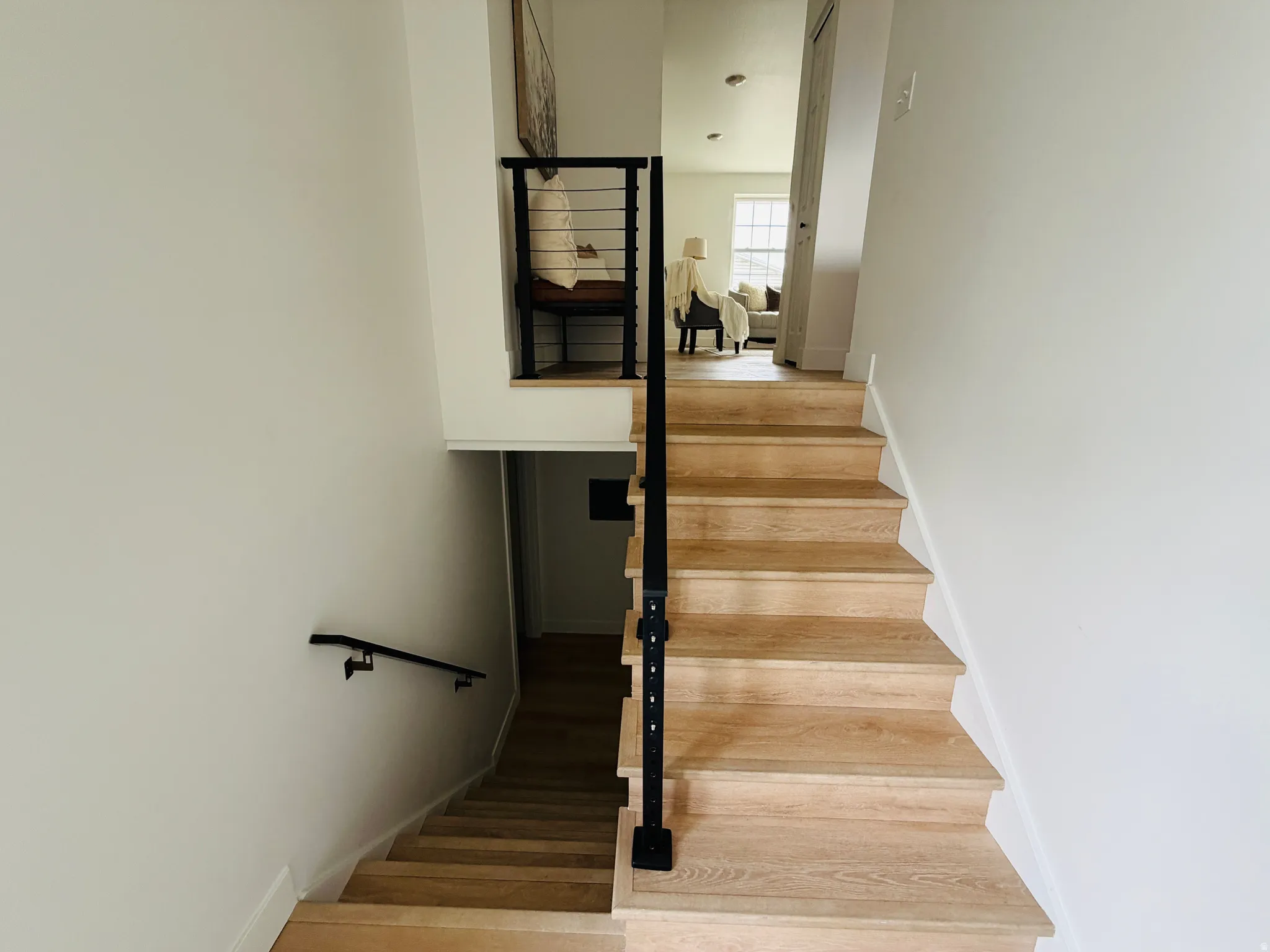 Light wood-finish staircase with black metal railing