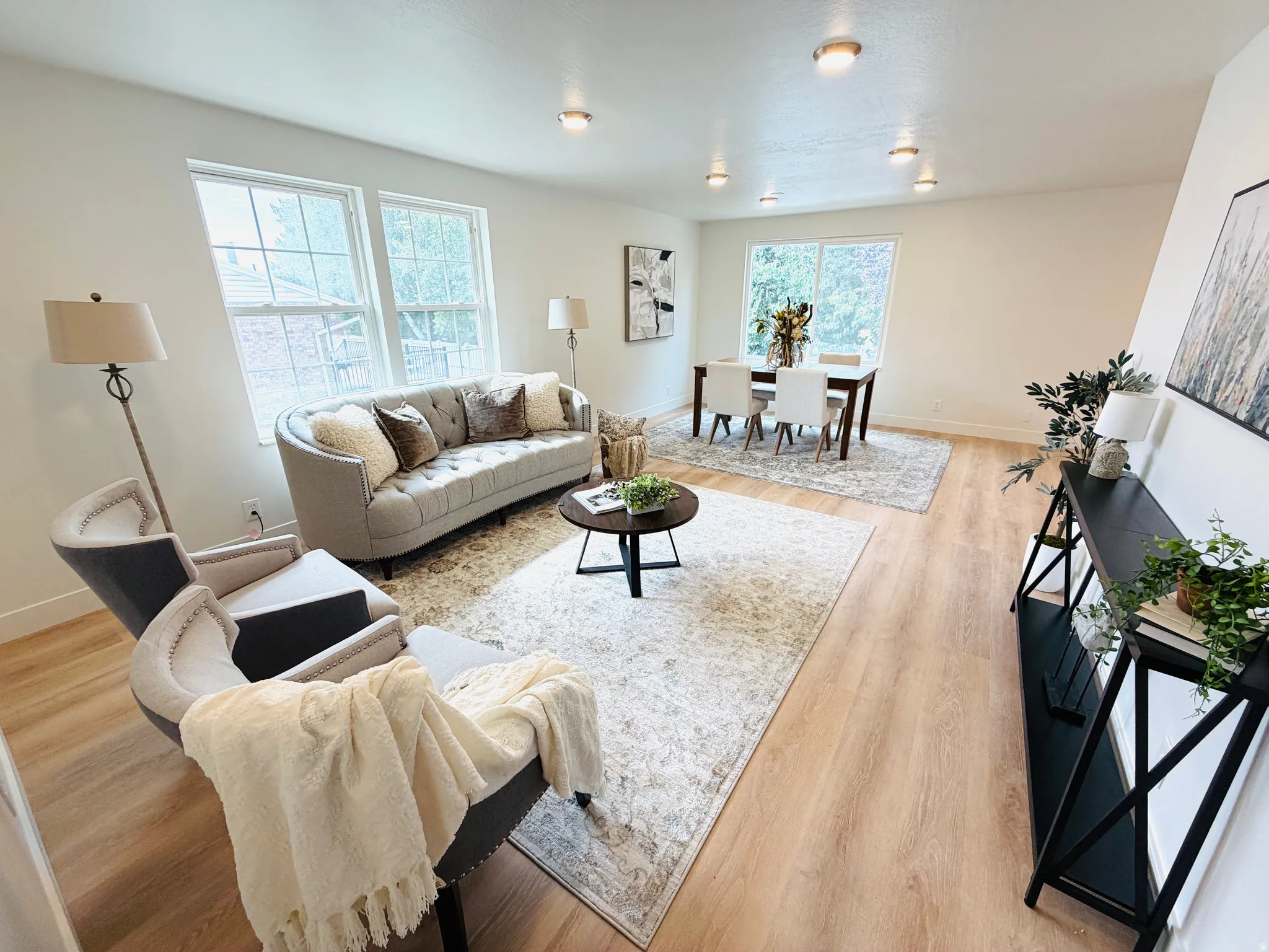 Open-concept living space featuring wood-finish flooring, recessed lighting, and multiple windows