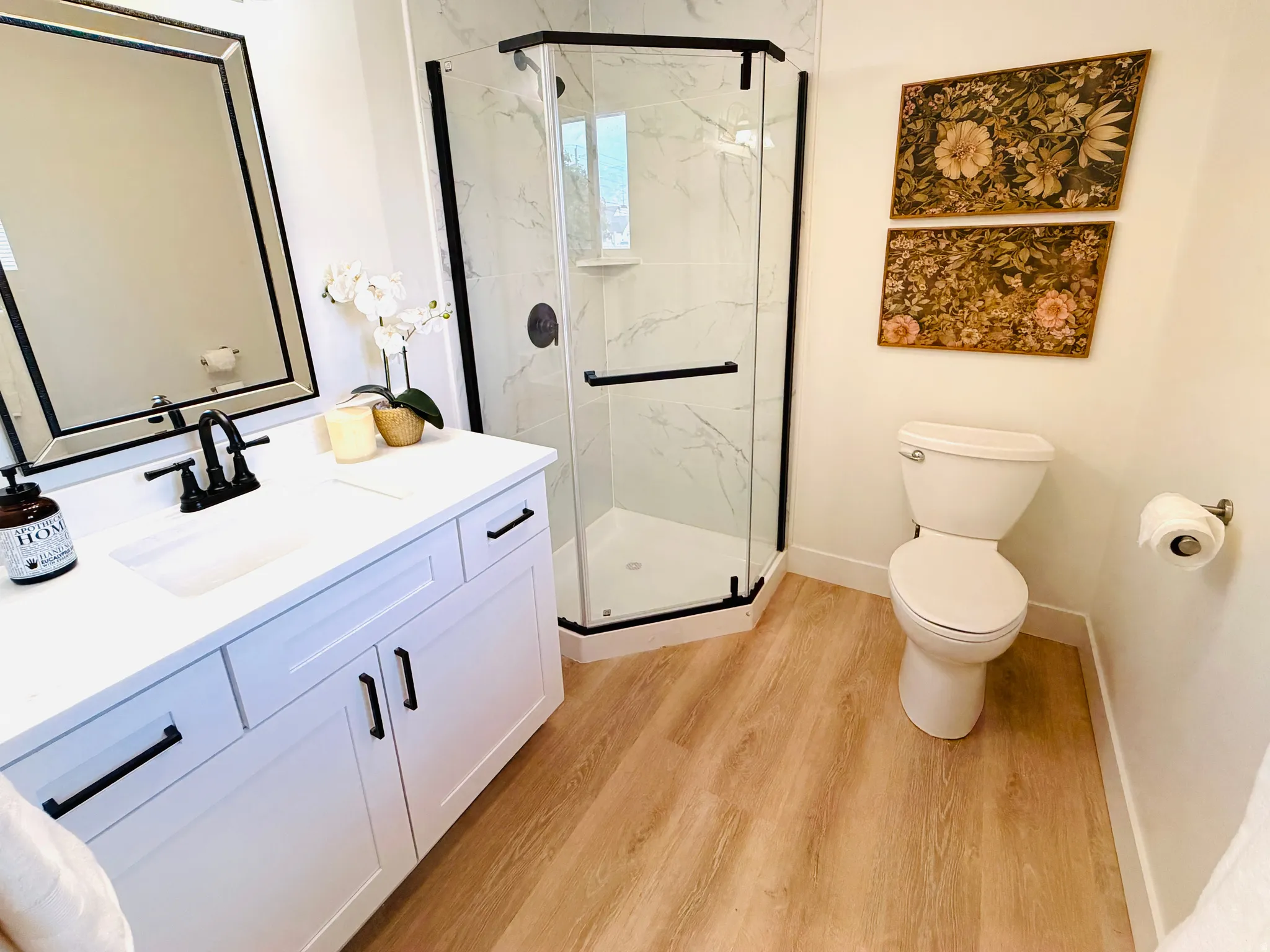 Bathroom featuring a white vanity with integrated sink, black hardware, and a framed mirror