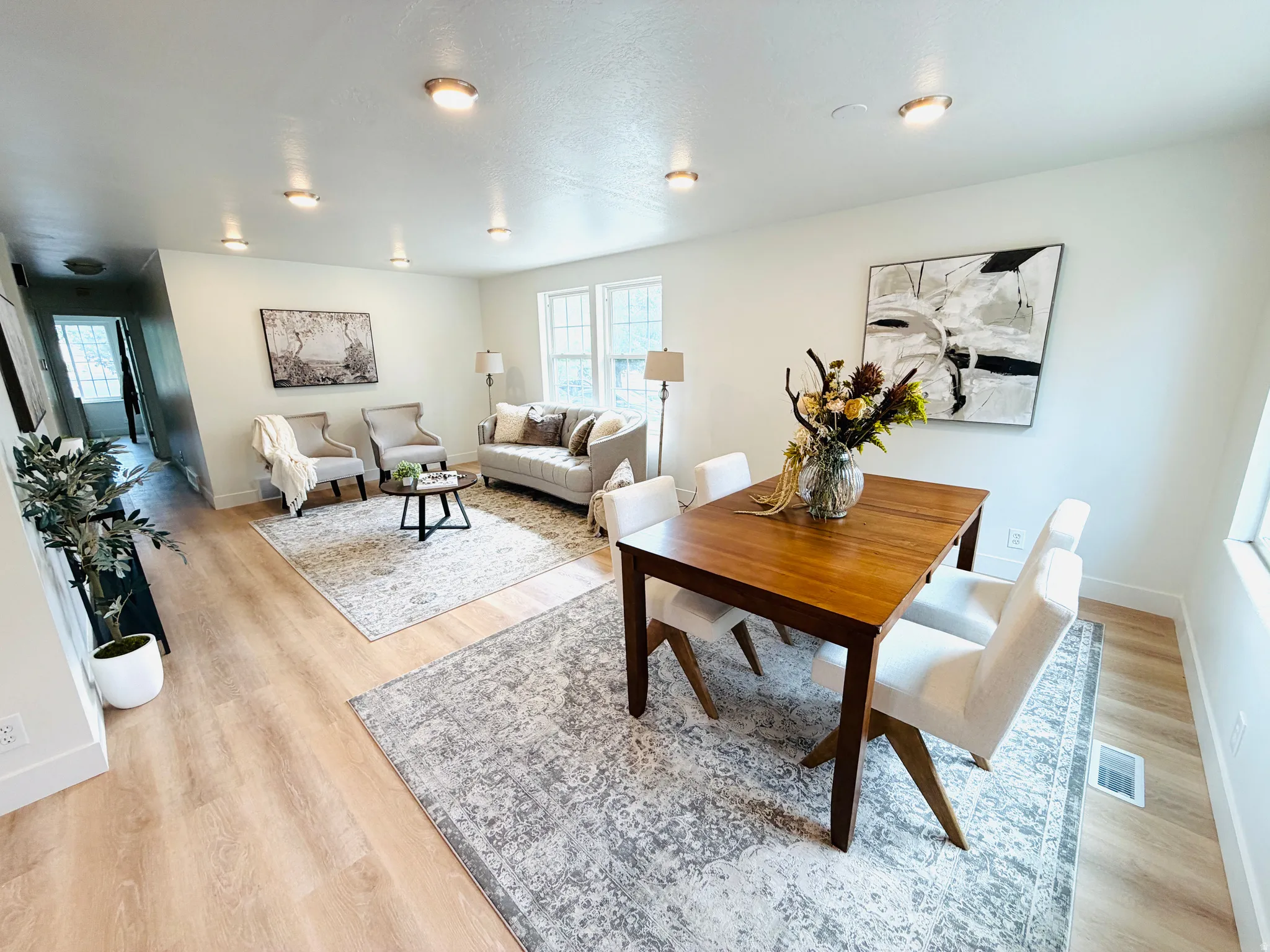 Open-concept living space featuring light wood-finish flooring, recessed lighting, white baseboards, and multiple windows providing natural light