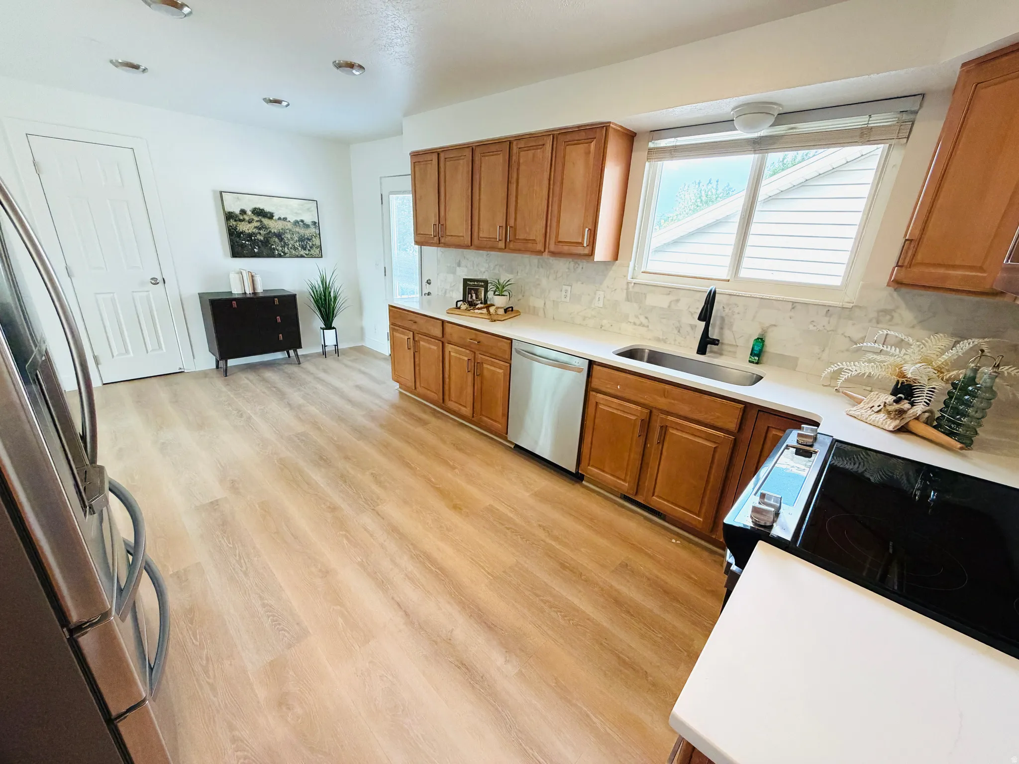 Kitchen featuring wood-finish flooring, wood cabinetry, white countertops, and a tile backsplash