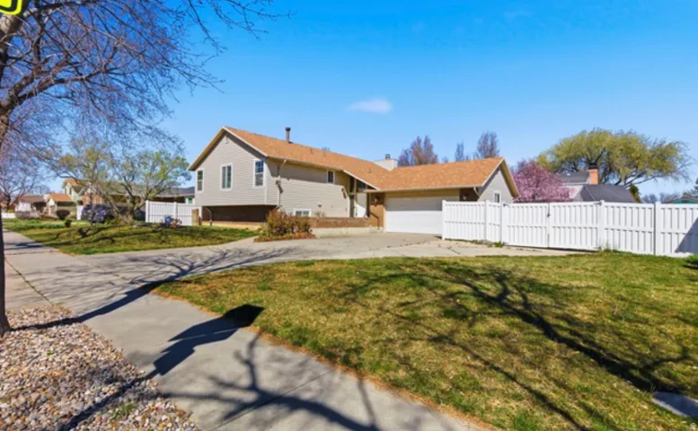 Split-level home featuring light-colored siding and a brown shingle roof