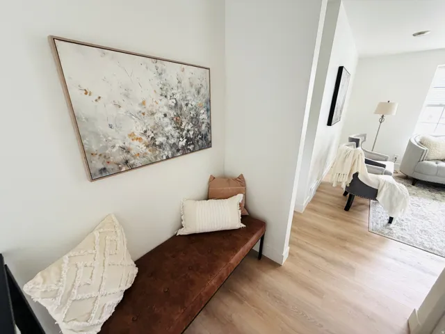 Light-toned wood-finish flooring extends through the entryway, complemented by white baseboards and walls