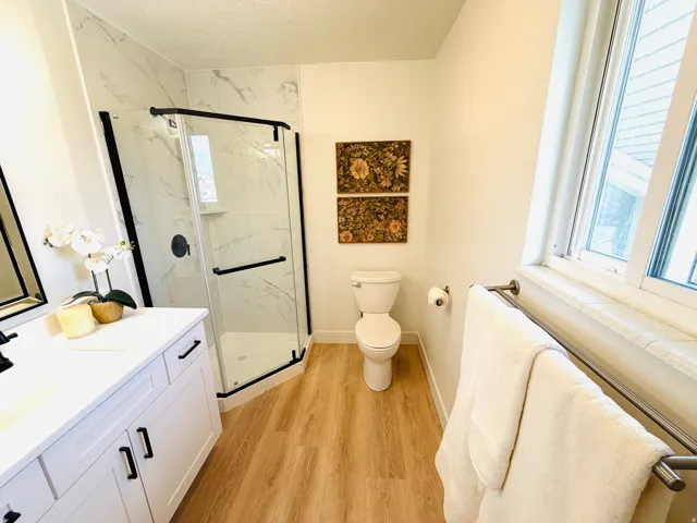 Bathroom featuring a corner glass-enclosed shower with black framing, white marble-style subway tile, and a built-in shower niche