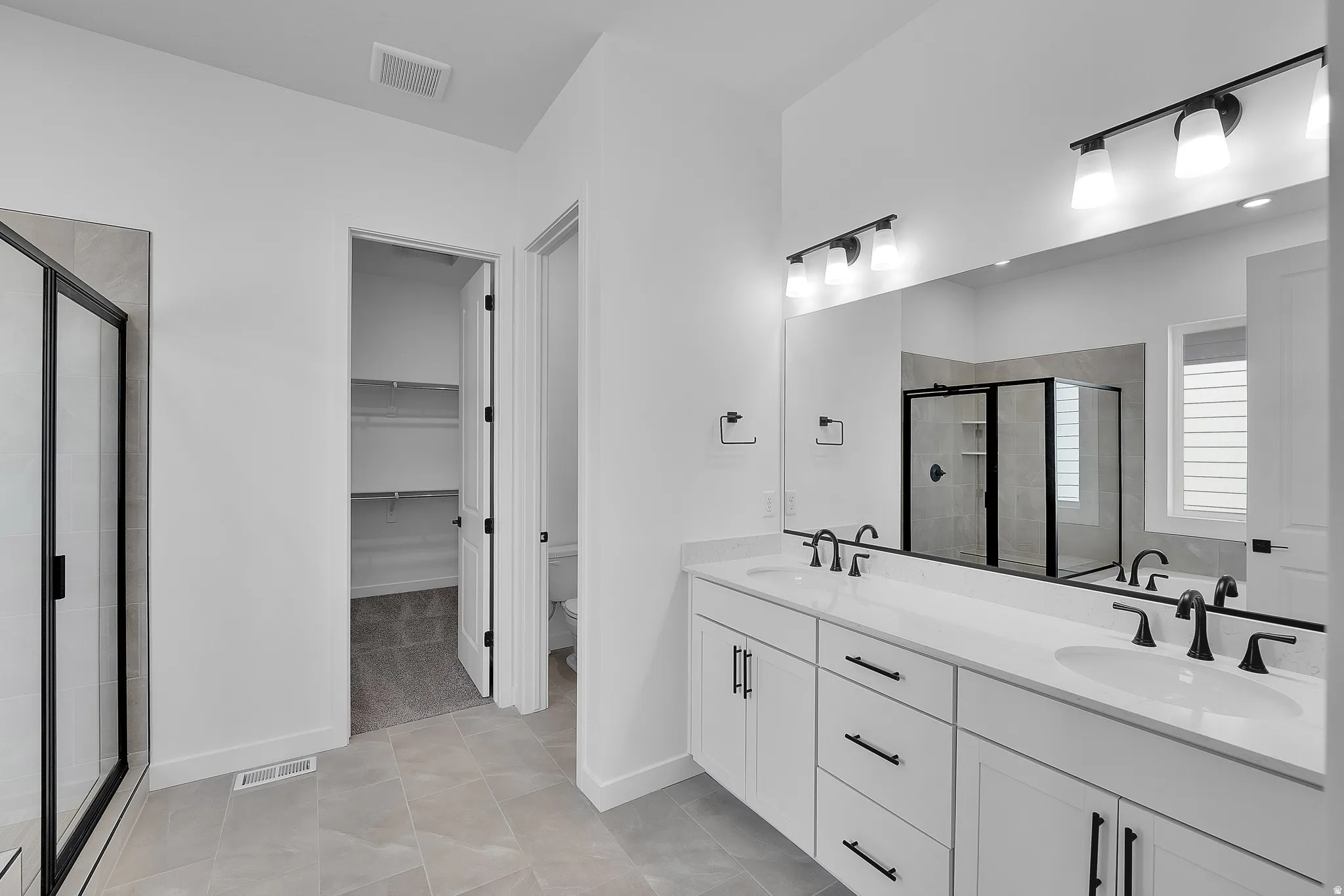 Contemporary bathroom featuring a double vanity with white cabinetry, quartz countertops, and matte black fixtures