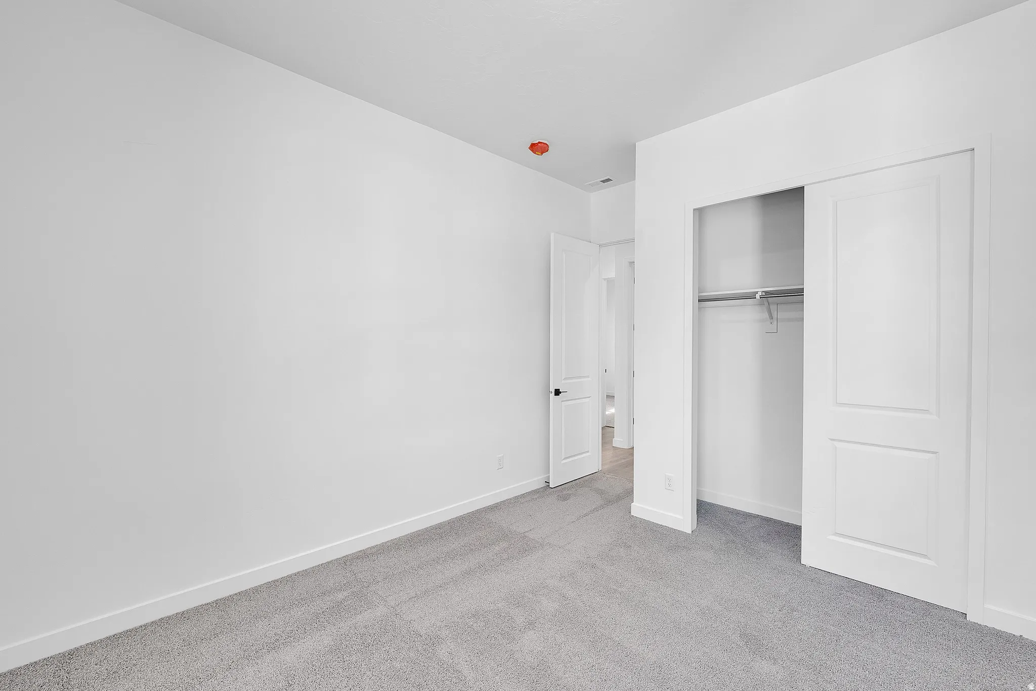 Room featuring light gray carpeting, white painted walls, and a white baseboard trim