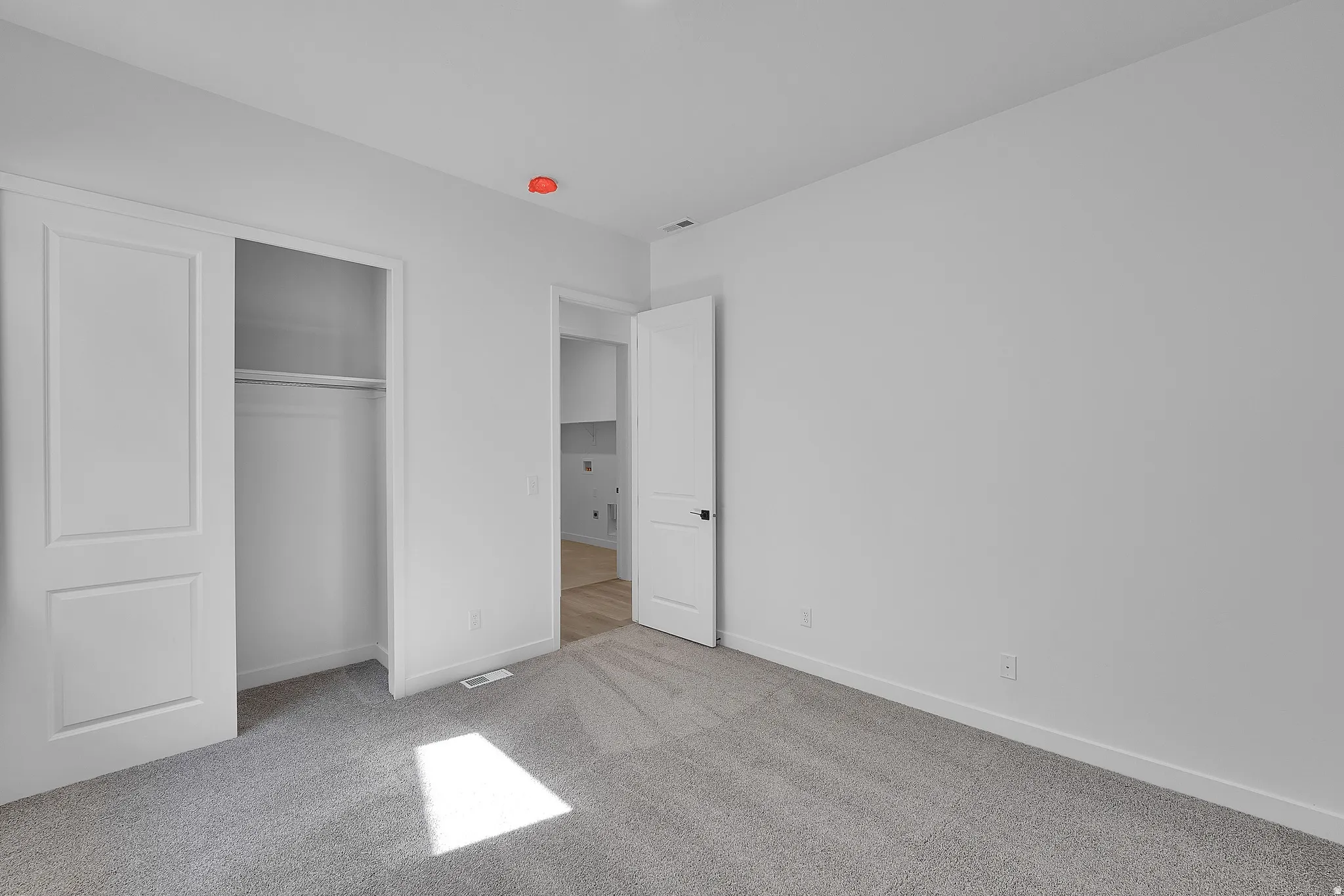 Carpeted room with white walls, a bi-fold closet, and a white door featuring black hardware