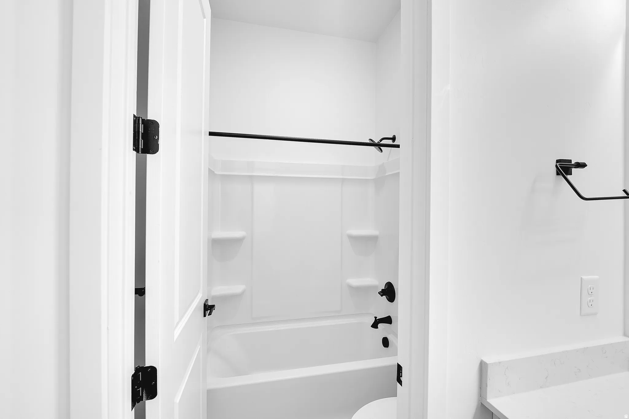 White bathtub with integrated shelving and matte black fixtures