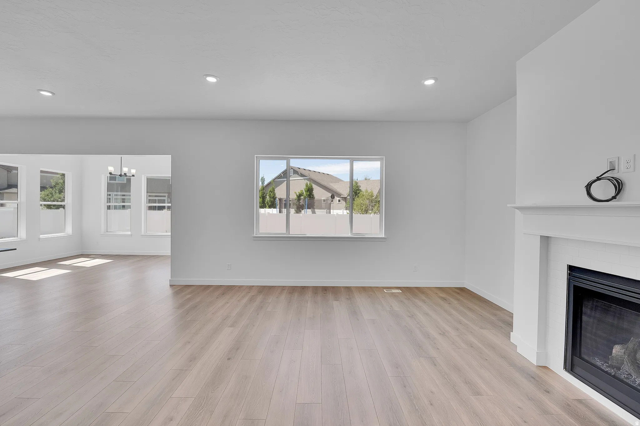 Living area featuring light wood-finish flooring, recessed lighting, and a white mantel fireplace