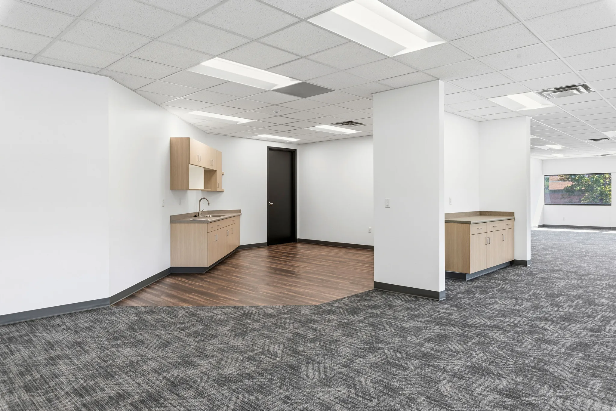 Open-concept commercial space featuring a built-in wet bar with a stainless steel sink and light wood cabinetry