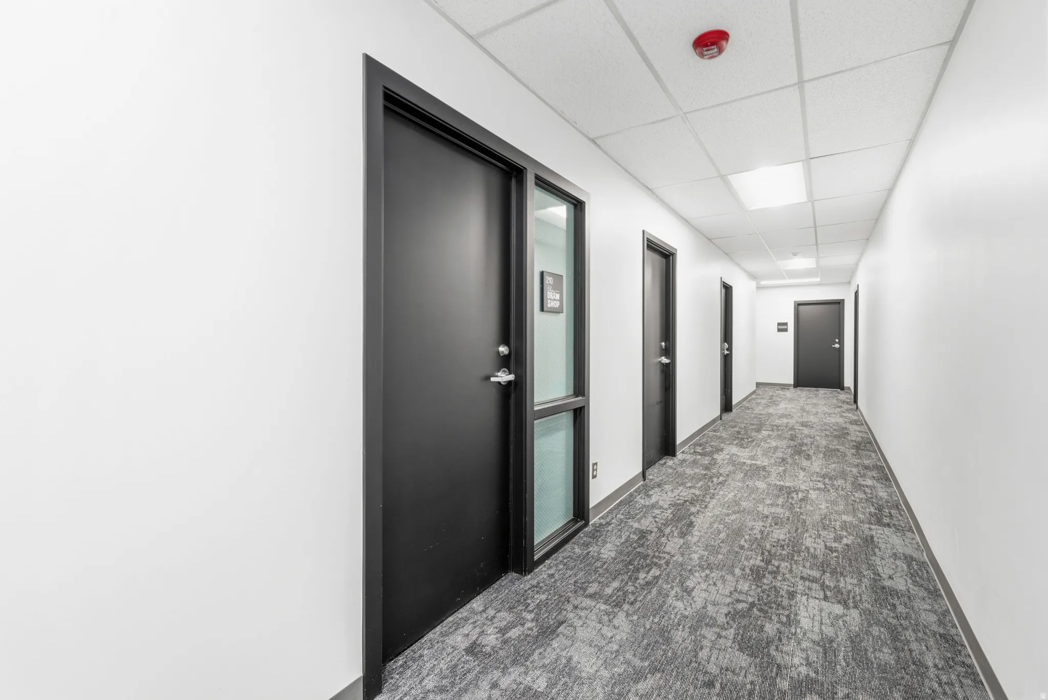Hallway featuring white walls and a drop ceiling with recessed lighting
