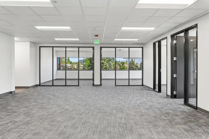 Open-concept commercial space featuring gray patterned carpeting and a white acoustic tile ceiling with integrated rectangular lighting