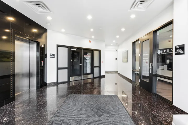 Lobby featuring polished dark granite flooring, recessed lighting, and a stainless steel elevator