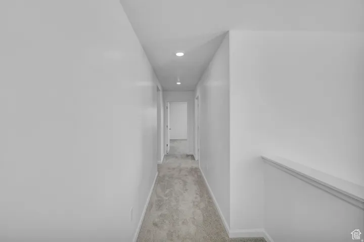 Bright hallway featuring recessed lighting and neutral-toned carpeting
