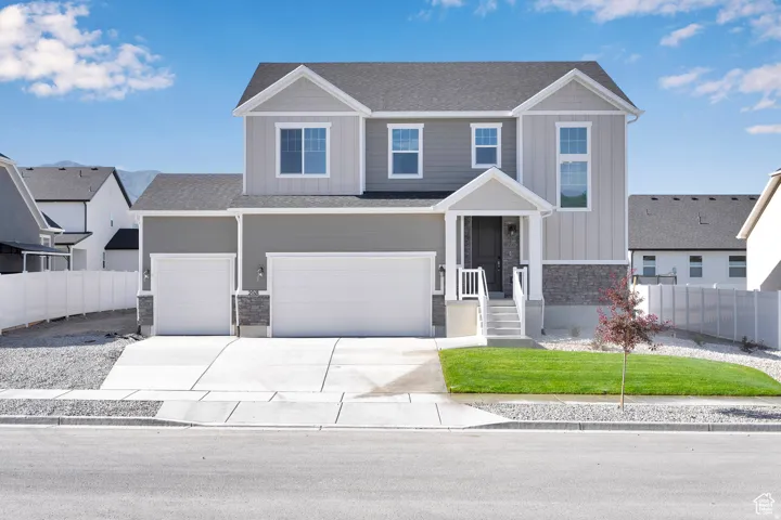 Modern two-story residence featuring a two-car garage, covered entry porch with white railings, and a contrasting light and dark grey siding facade