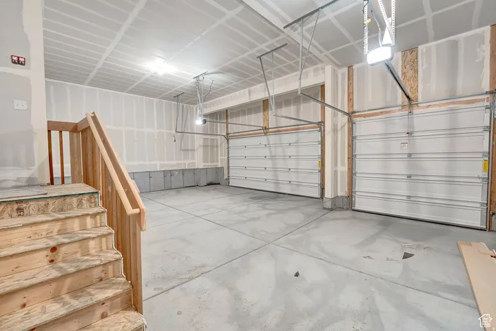 Spacious garage featuring two overhead doors, concrete flooring, and bare wood framing