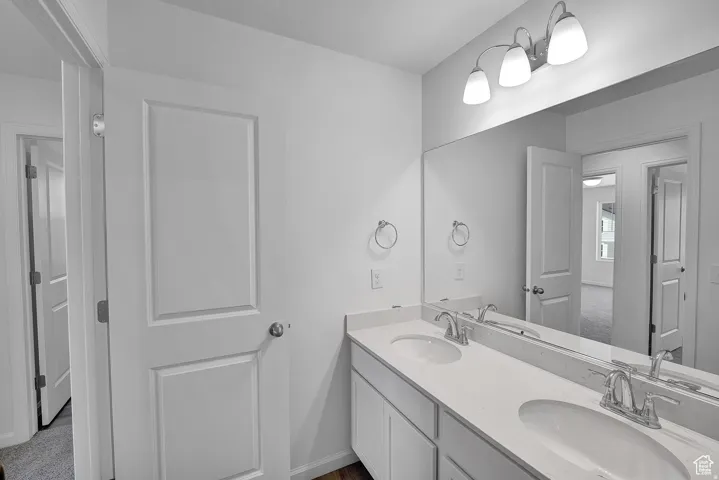 Double vanity featuring dual undermount sinks, chrome fixtures, and a white countertop
